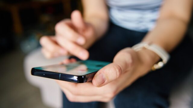 Person scrolling on smartphone researching paid social vs programmatic - Dig & Dig
