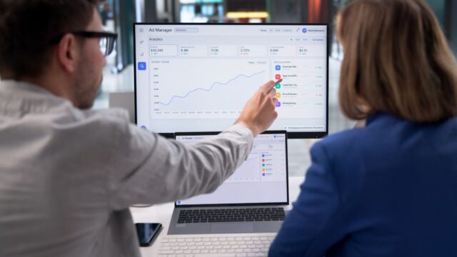 Two Dig & Dig agency workers looking at a computer screen discussing paid social and programmatic strategy - Dig & Dig